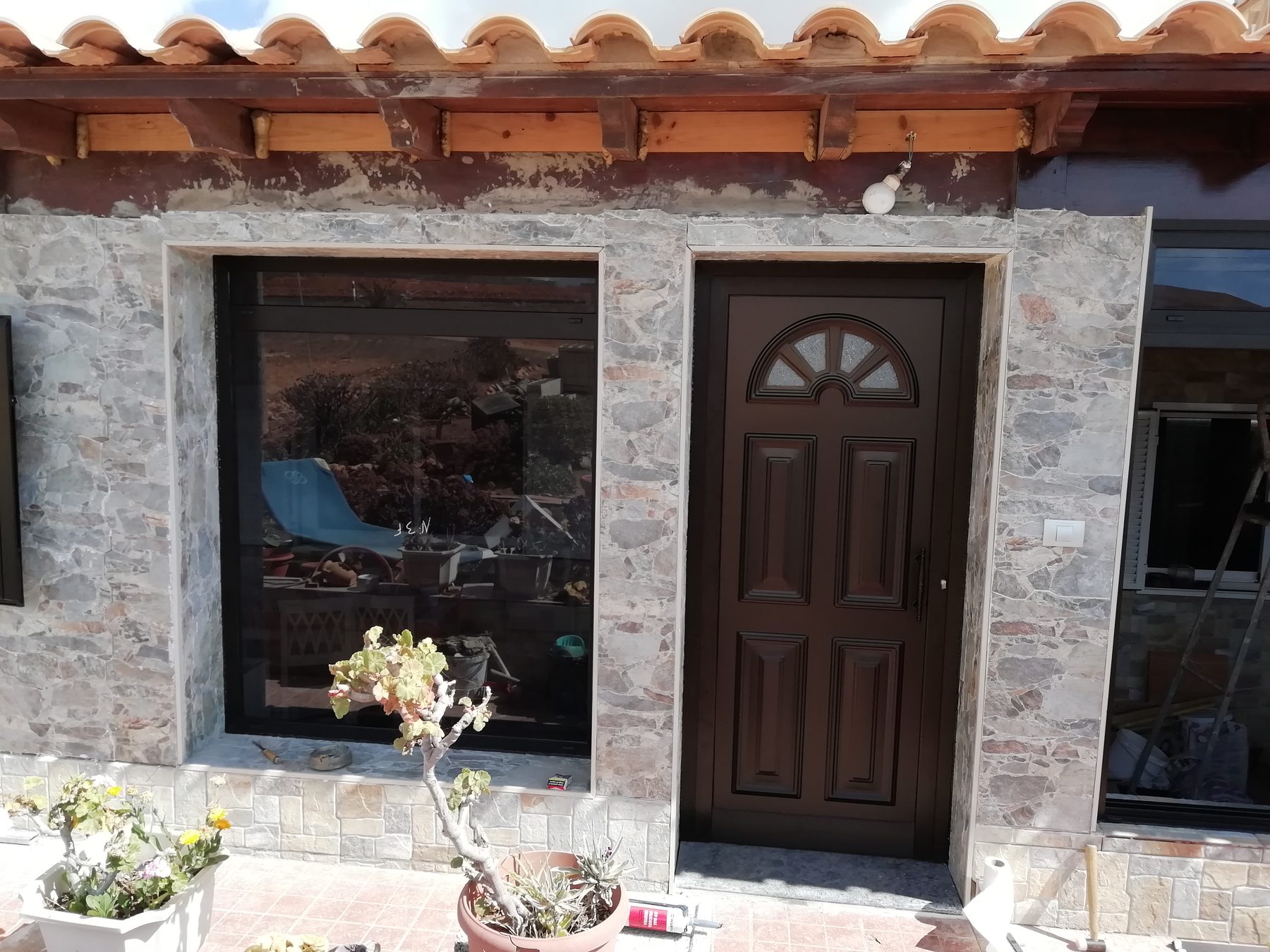 Puerta de entrada de aluminio imitación madera en fachada de piedra