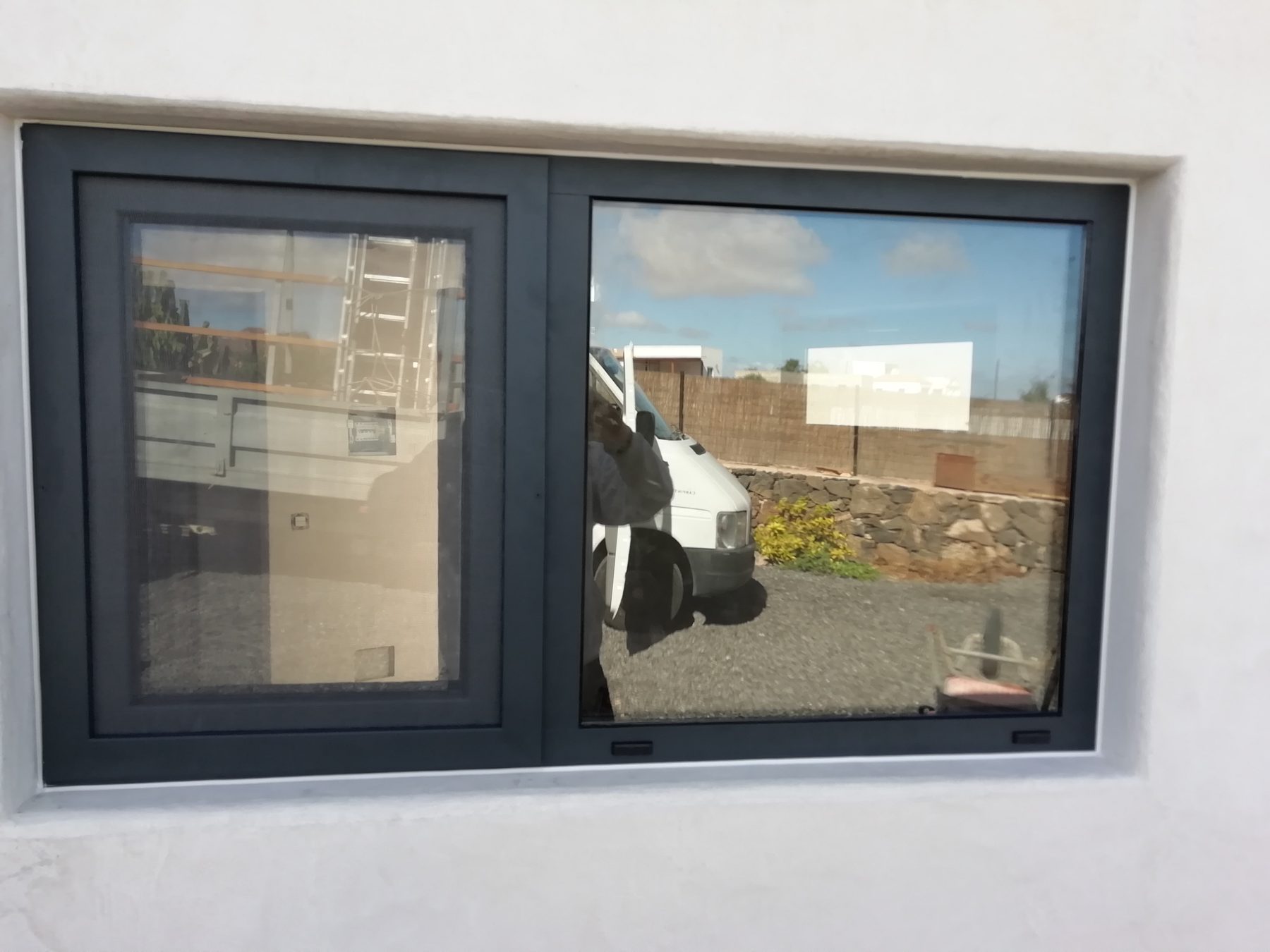 Ventana abisagrada de aluminio negro en fachada blanca
